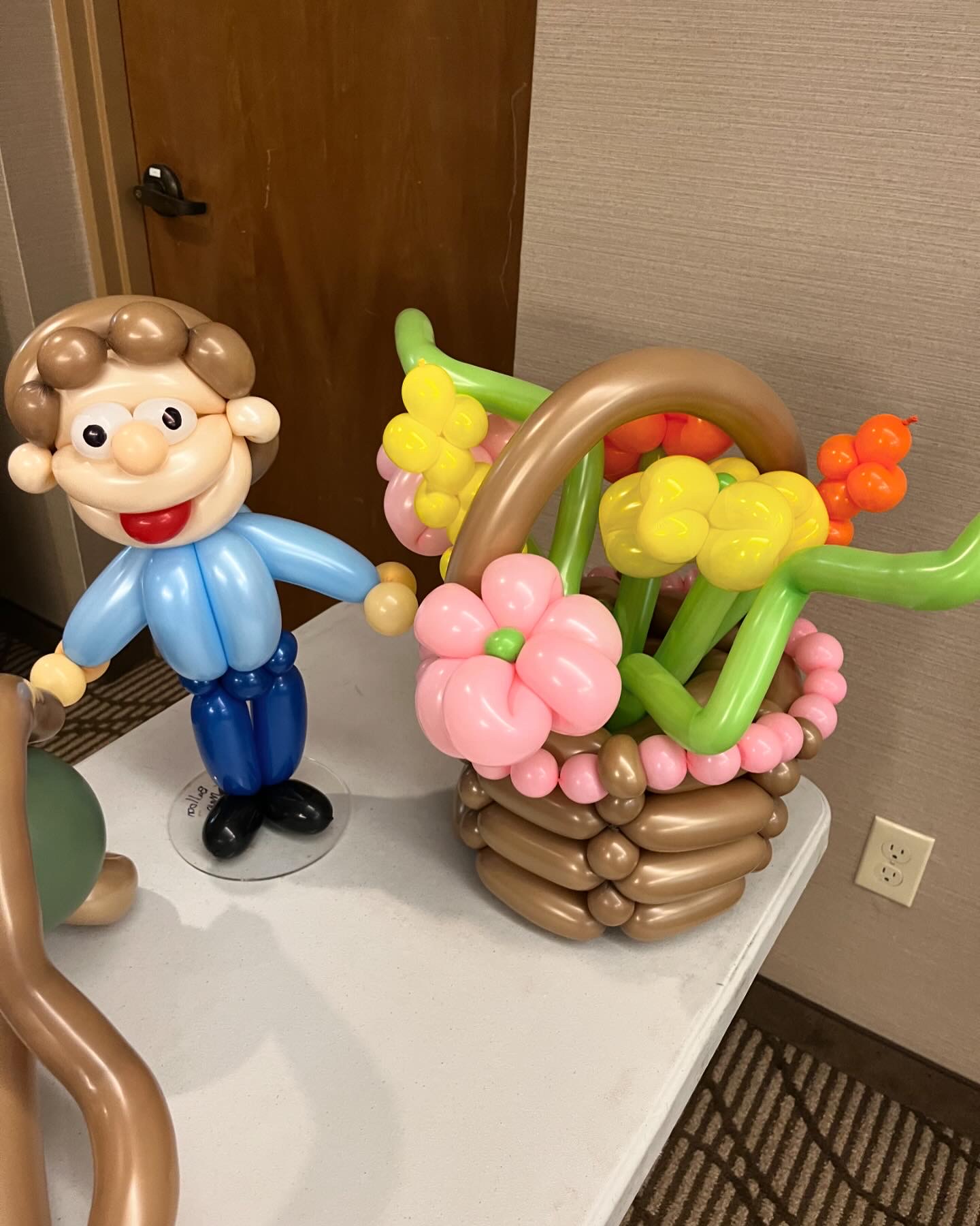 Balloon flower basket with pink and yellow blooms next to a balloon man
