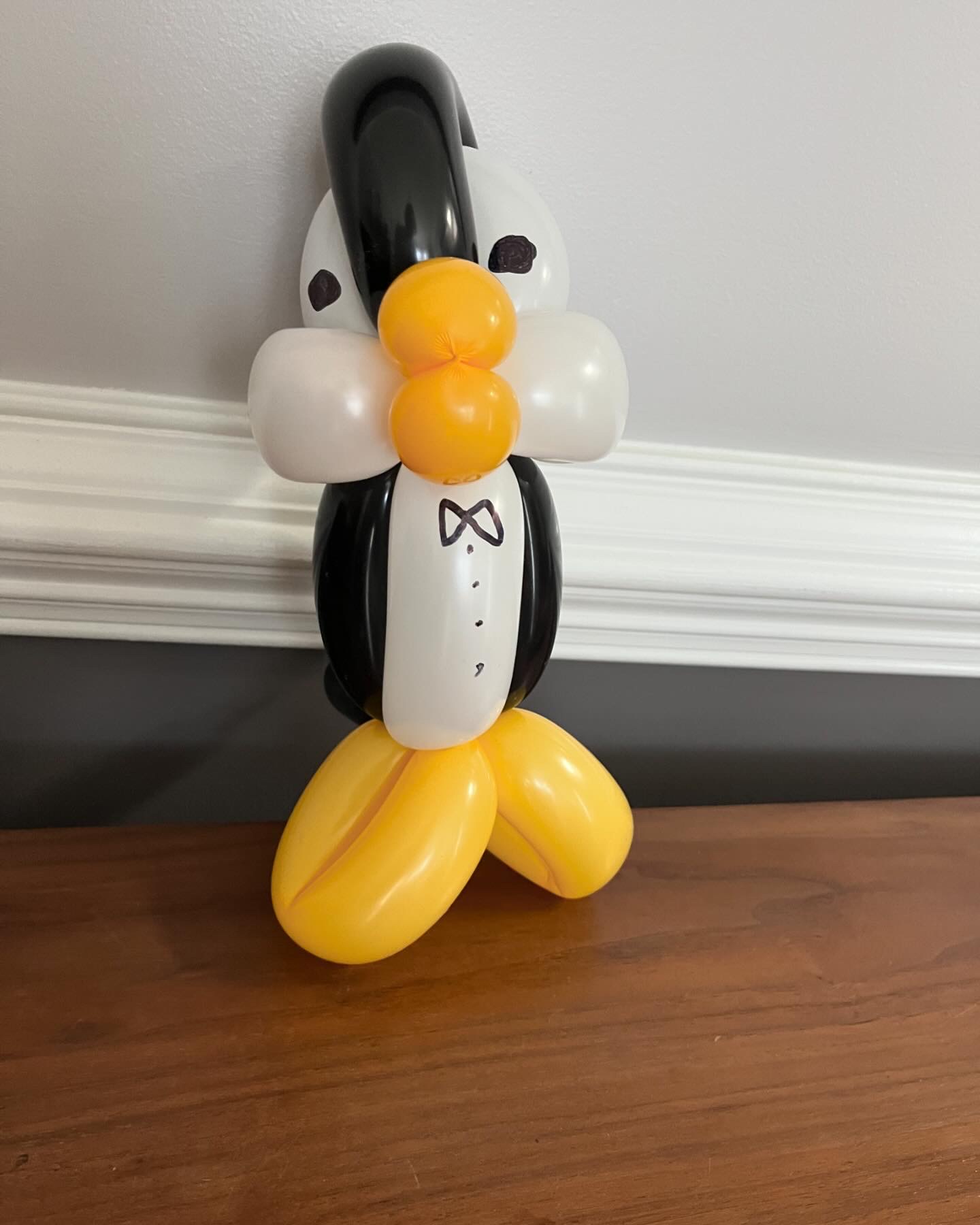 Tall balloon penguin in a tuxedo with yellow feet